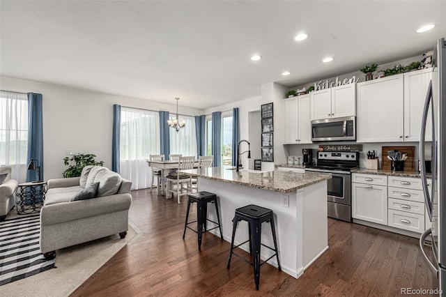 9350 Dunraven St, Arvada, CO 80007 - kitchen with appliances with stainless steel finishes, a chandelier, light stone countertops, a kitchen breakfast bar, and a sink