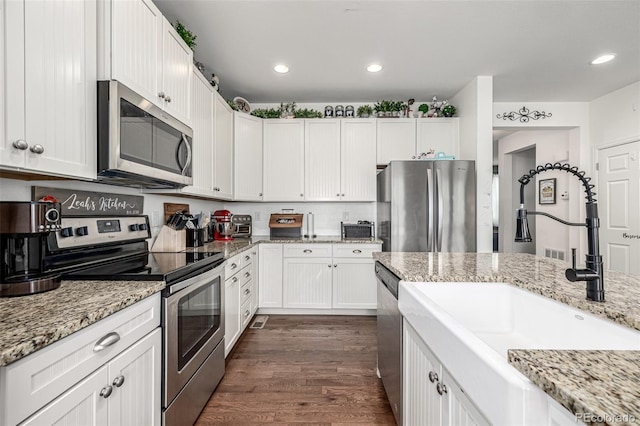 9350 Dunraven St, Arvada, CO 80007 - kitchen with stainless steel appliances, a sink, dark wood-style flooring, white cabinets, and light stone countertops