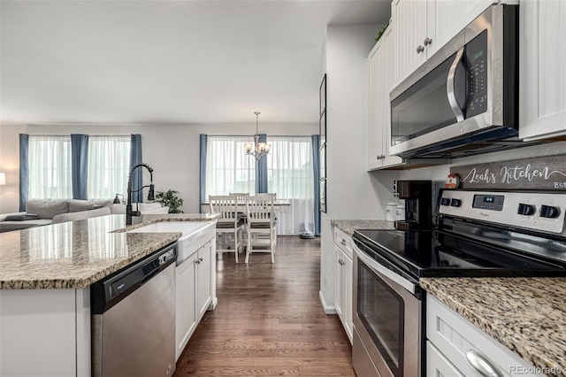 9350 Dunraven St, Arvada, CO 80007 - kitchen with appliances with stainless steel finishes, a sink, dark wood-style flooring, white cabinets, and a chandelier