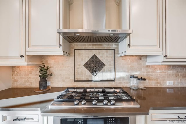 kitchen with white cabinets, stainless steel gas stovetop, wall chimney range hood, and tasteful backsplash