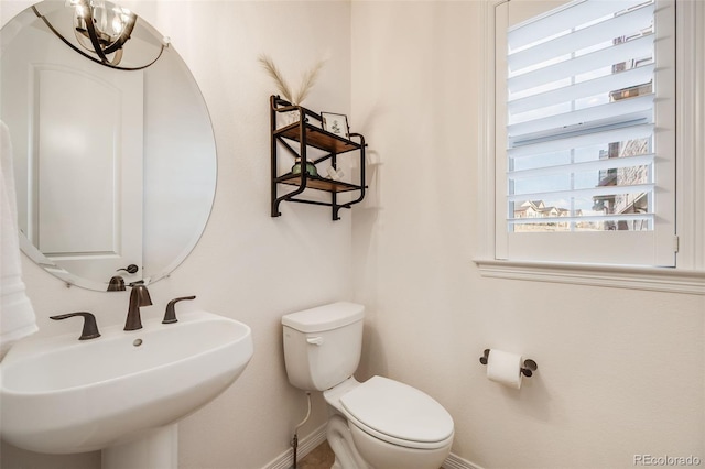 bathroom featuring toilet, sink, and a chandelier