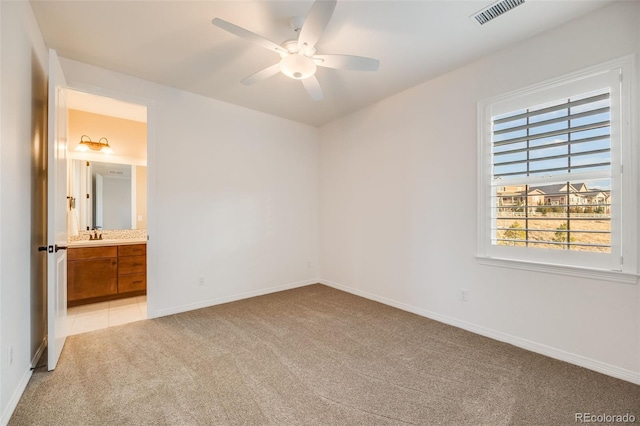 unfurnished bedroom featuring connected bathroom, ceiling fan, and light colored carpet