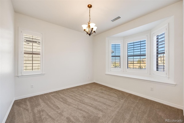 empty room with carpet flooring and a notable chandelier