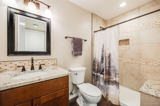 bathroom with vanity, tasteful backsplash, toilet, and walk in shower