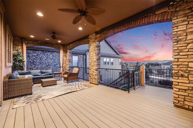 deck at dusk with ceiling fan and an outdoor hangout area