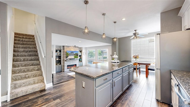 4826 S Ireland St, Aurora, CO 80015 - kitchen with stainless steel appliances, gray cabinets, dark wood-style flooring, a fireplace, and a kitchen island