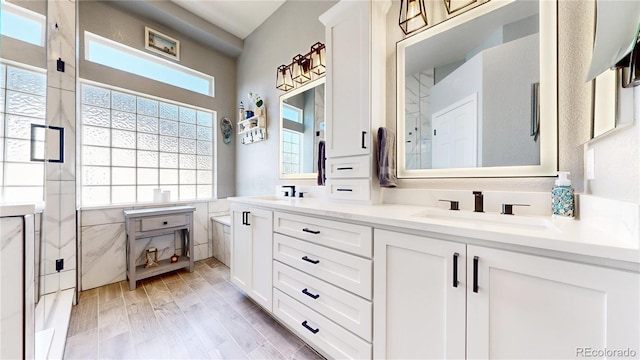 4826 S Ireland St, Aurora, CO 80015 - full bathroom with double vanity, wood finished floors, an enclosed shower, and tile walls