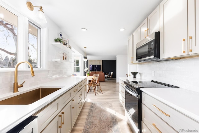 kitchen featuring a sink, white cabinetry, light countertops, appliances with stainless steel finishes, and light wood-type flooring