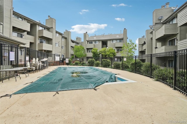 community pool featuring fence, a patio, and a residential view