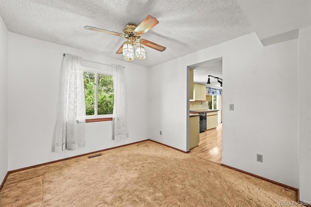 unfurnished room featuring light colored carpet, a textured ceiling, baseboards, and ceiling fan