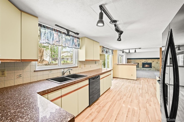 kitchen featuring black appliances, a sink, cream cabinets, rail lighting, and a textured ceiling