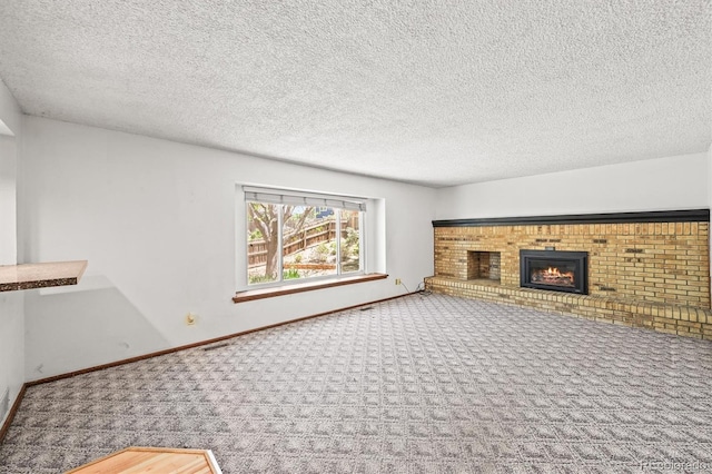 unfurnished living room with carpet flooring, a fireplace, a textured ceiling, and baseboards
