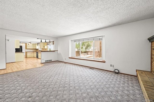 unfurnished living room featuring carpet floors, baseboards, and a textured ceiling
