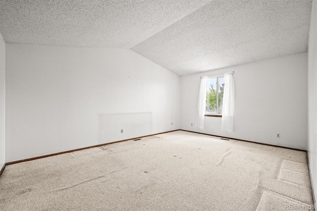 carpeted spare room featuring vaulted ceiling, baseboards, and a textured ceiling
