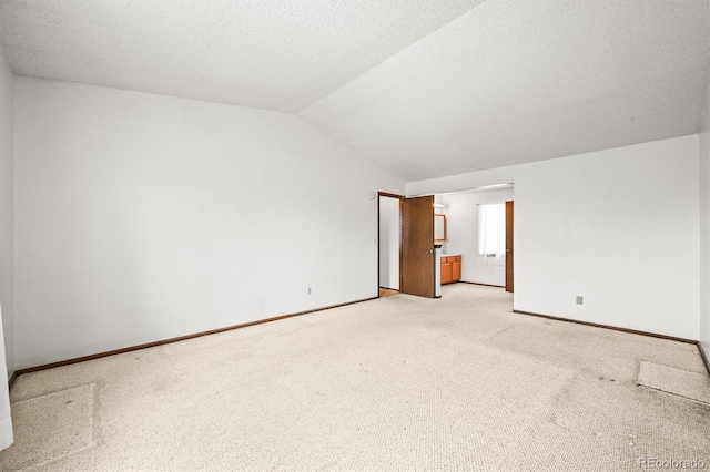 unfurnished room featuring vaulted ceiling, light carpet, and baseboards
