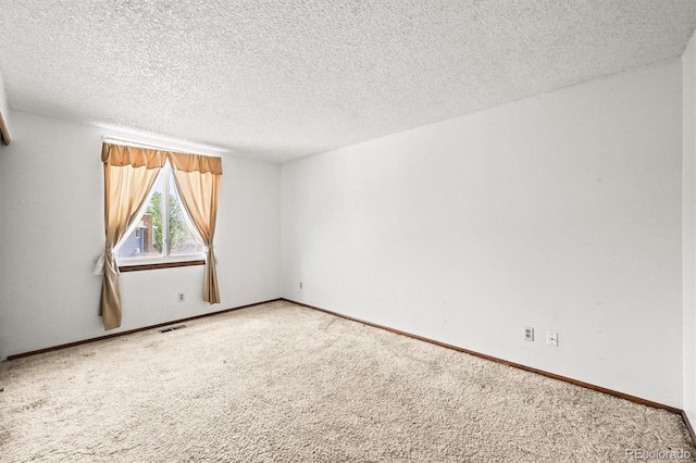 empty room with a textured ceiling, carpet, and baseboards
