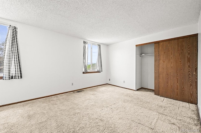 unfurnished bedroom featuring carpet, a textured ceiling, a closet, and baseboards