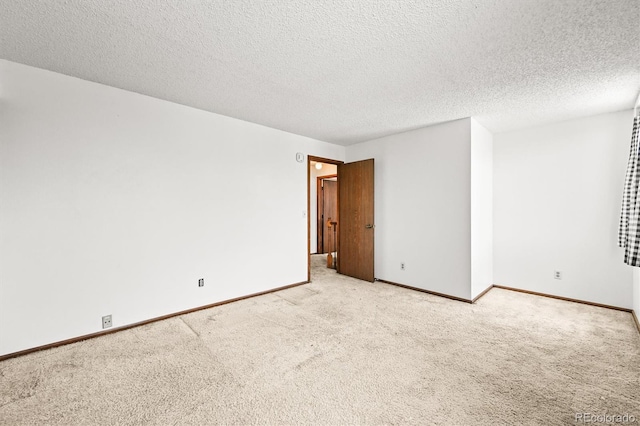 spare room featuring carpet floors, baseboards, and a textured ceiling