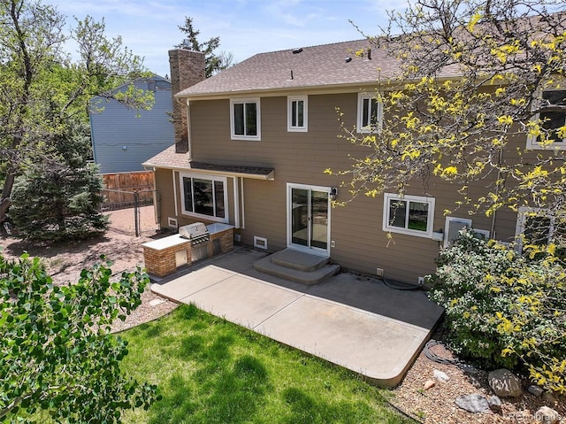 rear view of house with exterior kitchen, a patio, fence, a chimney, and a shingled roof