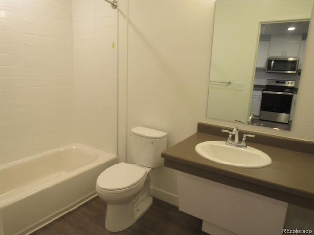 bathroom with toilet, bathtub / shower combination, wood finished floors, and vanity