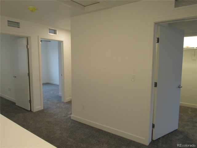 hall featuring baseboards, visible vents, and dark colored carpet