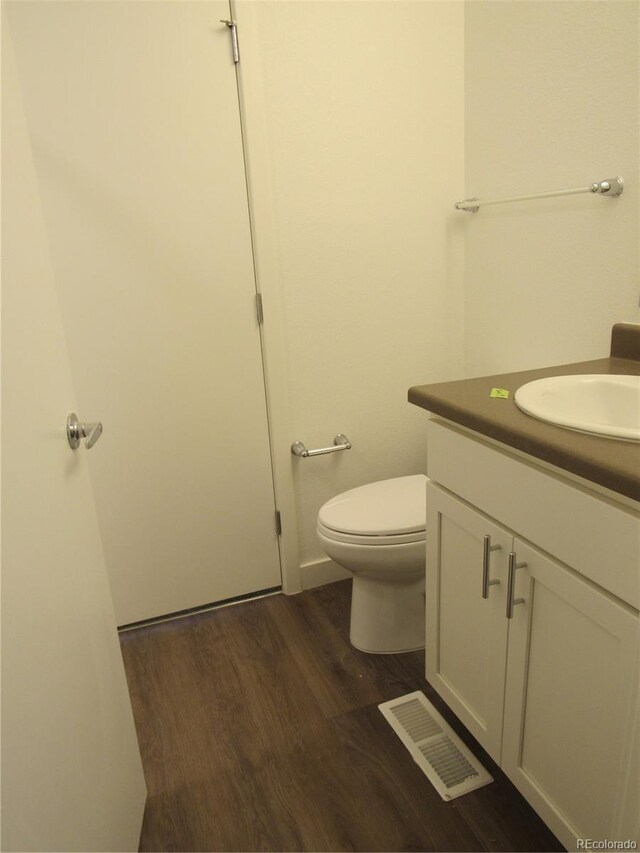 bathroom featuring vanity, toilet, and hardwood / wood-style flooring