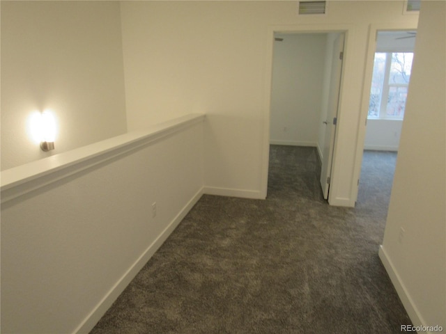 hallway with baseboards, visible vents, and dark carpet