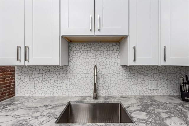 kitchen with white cabinets, decorative backsplash, and light stone countertops