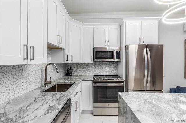 kitchen featuring appliances with stainless steel finishes, white cabinetry, decorative backsplash, and sink