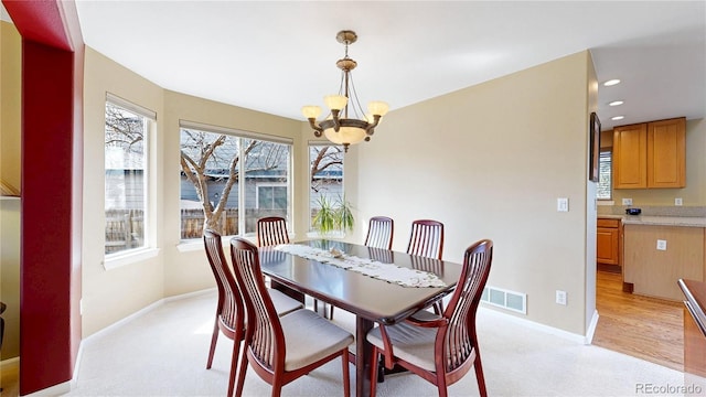 dining room with a chandelier, light colored carpet, visible vents, and baseboards