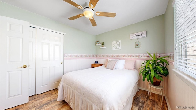 bedroom featuring a wainscoted wall, a closet, a ceiling fan, and wood finished floors