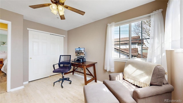 office featuring light wood-type flooring, a ceiling fan, and baseboards