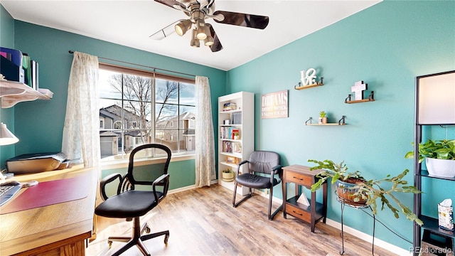 home office with light wood finished floors, a ceiling fan, and baseboards