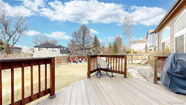 deck featuring a residential view, a grill, a fenced backyard, and a lawn