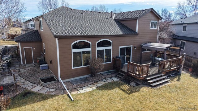 rear view of house featuring a lawn, roof with shingles, fence, a deck, and a pergola