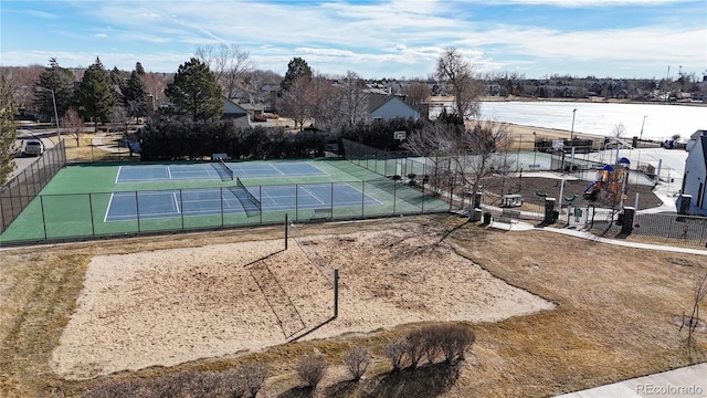 view of tennis court featuring a water view and fence