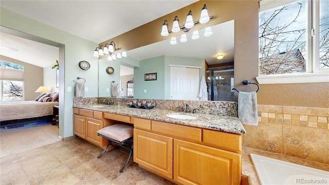 bathroom featuring double vanity, connected bathroom, vaulted ceiling, and a sink