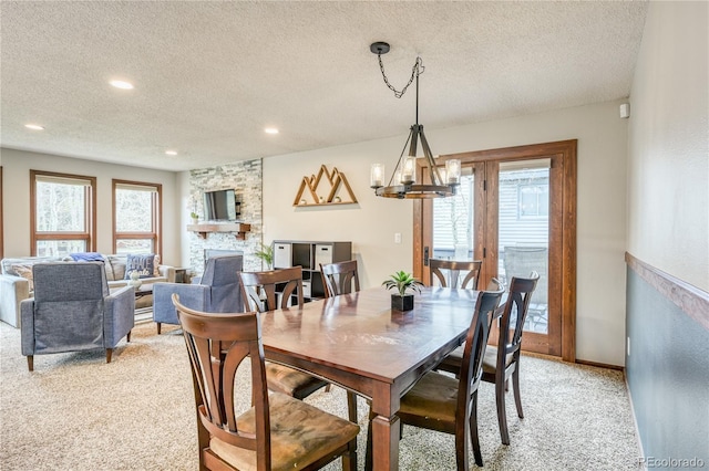140 Forest Dr, Frisco, CO 80443 - dining room featuring light carpet, a textured ceiling, a stone fireplace, a chandelier, and recessed lighting