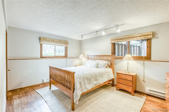 140 Forest Dr, Frisco, CO 80443 - bedroom featuring a baseboard radiator, light wood-style floors, rail lighting, and a textured ceiling