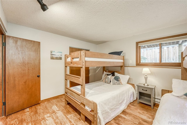 140 Forest Dr, Frisco, CO 80443 - bedroom featuring wood finished floors, a textured ceiling, baseboard heating, and baseboards