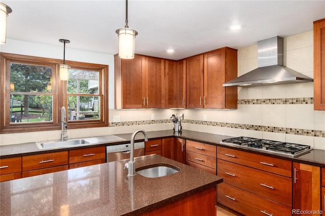 kitchen featuring wall chimney range hood, a sink, appliances with stainless steel finishes, brown cabinets, and recessed lighting