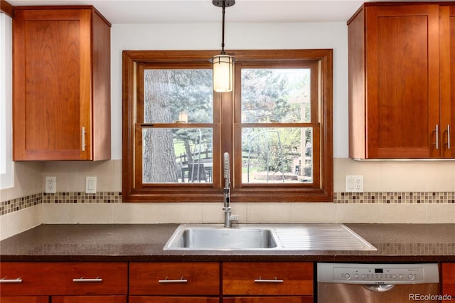 kitchen with stainless steel dishwasher, dark countertops, tasteful backsplash, and brown cabinets