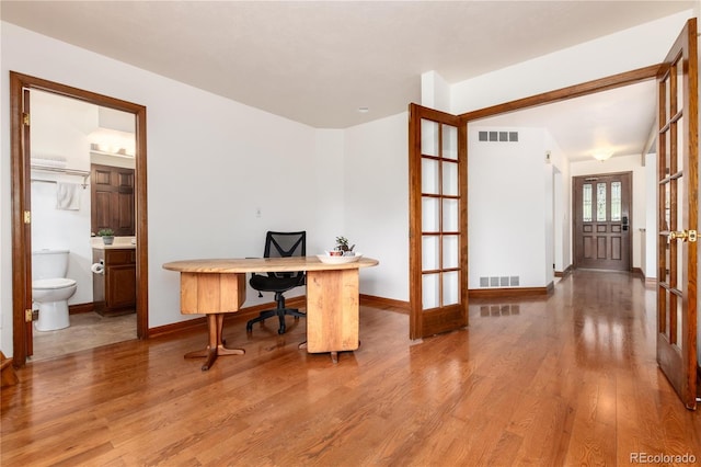 home office with wood finished floors, french doors, and baseboards