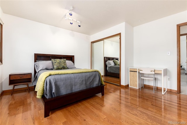 bedroom with wood finished floors, a closet, and baseboards