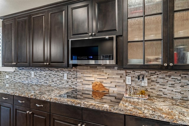 1609 S Catawba Cir, Aurora, CO 80018 - kitchen with stainless steel microwave, dark brown cabinetry, light stone counters, black electric cooktop, and tasteful backsplash