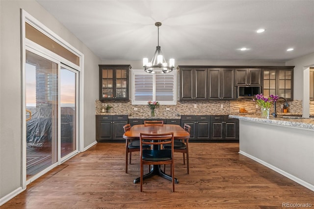 1609 S Catawba Cir, Aurora, CO 80018 - kitchen with a chandelier, decorative backsplash, glass insert cabinets, dark wood-type flooring, and recessed lighting