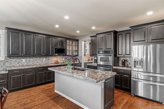 1609 S Catawba Cir, Aurora, CO 80018 - kitchen with stainless steel appliances, dark wood finished floors, backsplash, a center island with sink, and glass insert cabinets