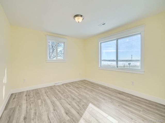 empty room with light hardwood / wood-style floors and plenty of natural light