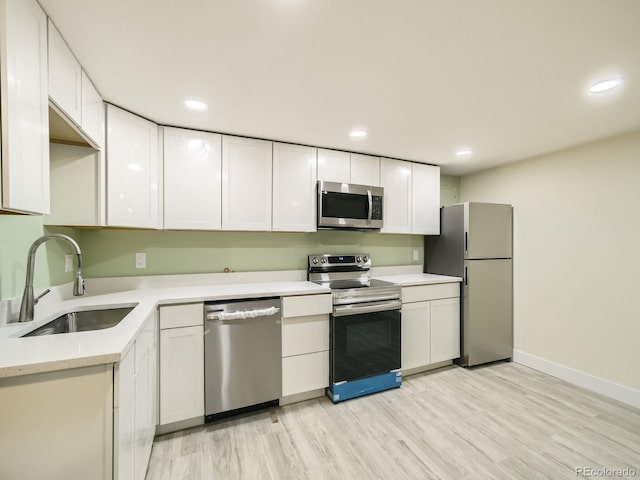 kitchen with sink, light hardwood / wood-style floors, white cabinetry, and appliances with stainless steel finishes