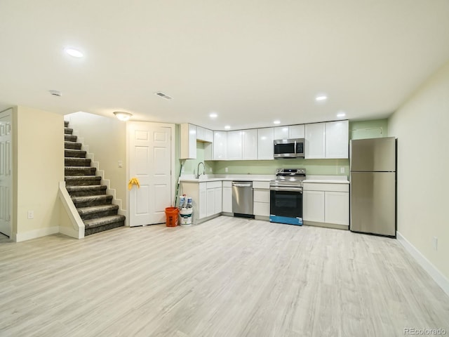 kitchen featuring sink, white cabinets, light hardwood / wood-style flooring, and stainless steel appliances